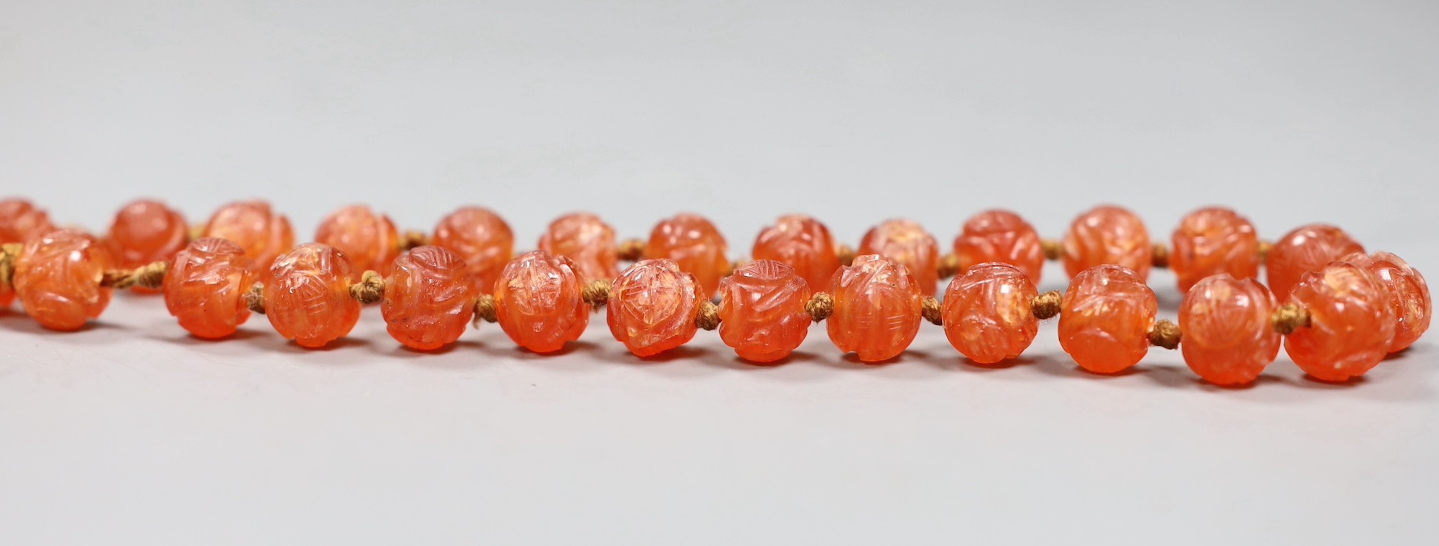 A Chinese chalcedony bead necklace, carved with medallion motifs, early 20th century